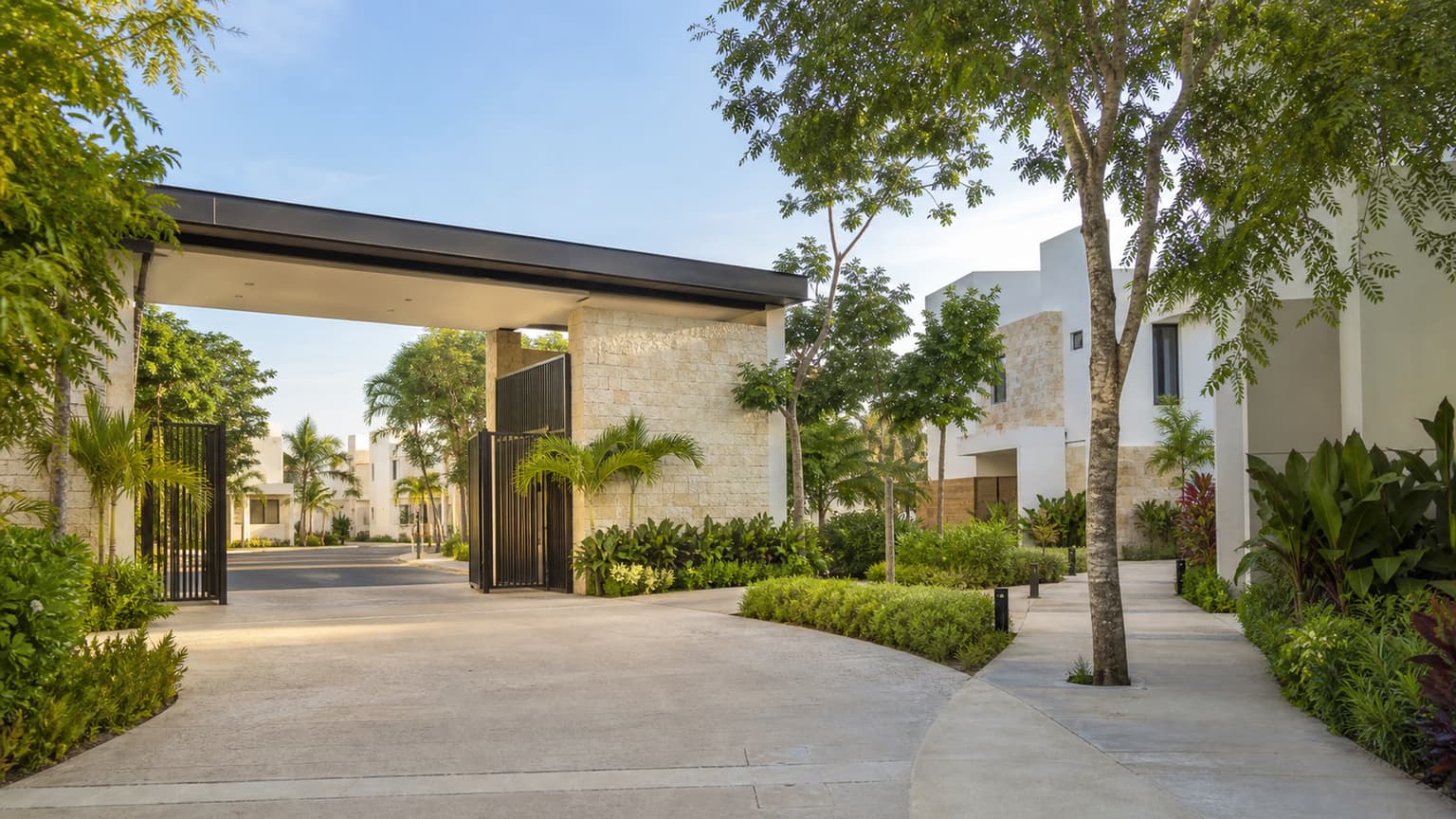 Entrada arbolada de una privada residencial moderna en Mérida